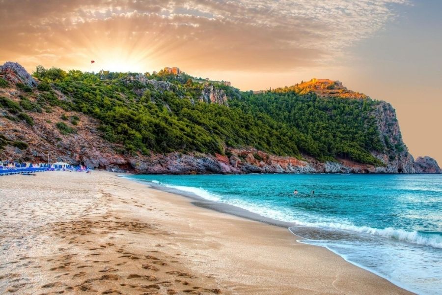 Клеопатра Alanya Местоположение и легенда Пляж протянулся примерно на 2–2,5 км вдоль берега Аланьи, в тени массивных скал, прямо под древней крепостью. По легенде, Римский полководец Марк Антоний подарил этот берег Клеопатре, которая использовала тут песок, завезённый из Египта .
